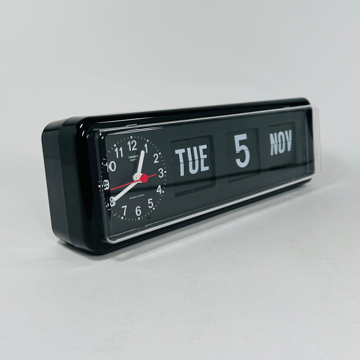 Retro black analog clock with clock face and vintage mechanical flip date, mid-century modern desk or wall clock